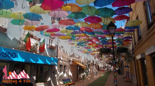 Hundreds of colorful umbrellas provide shade along this pedestrian street in Portugal