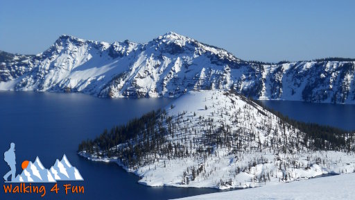 A snow-covered Crater Lake with Wizard Island in the middle.